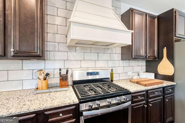 7730 Tiberon Pkwy, Cumming, GA 30028 - kitchen with decorative backsplash, custom exhaust hood, dark brown cabinetry, light stone counters, and stainless steel appliances
