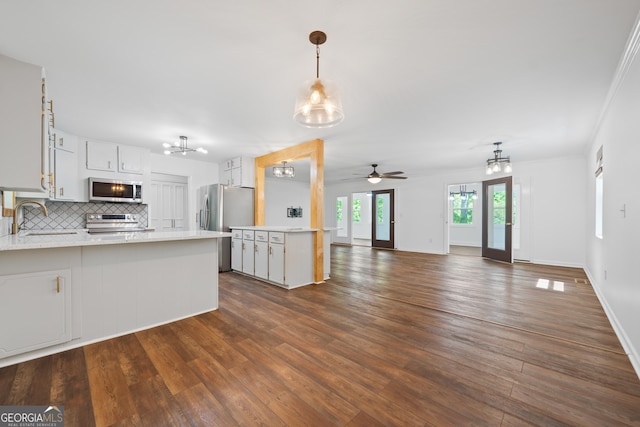 kitchen featuring appliances with stainless steel finishes, dark wood finished floors, a sink, light countertops, and a peninsula