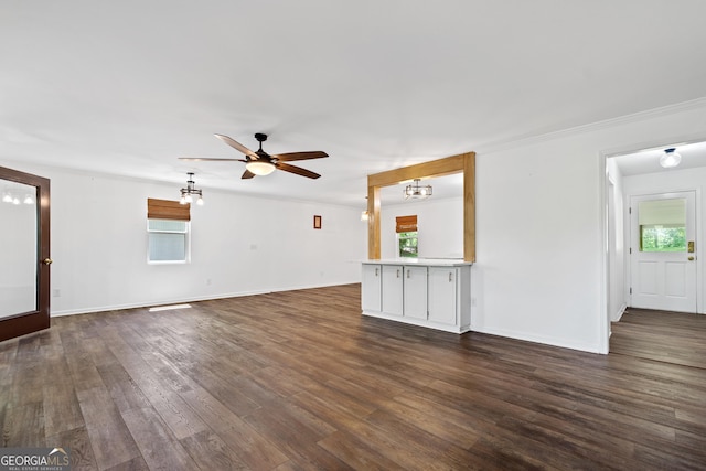 unfurnished living room with dark wood-style flooring, baseboards, a wealth of natural light, and ceiling fan with notable chandelier