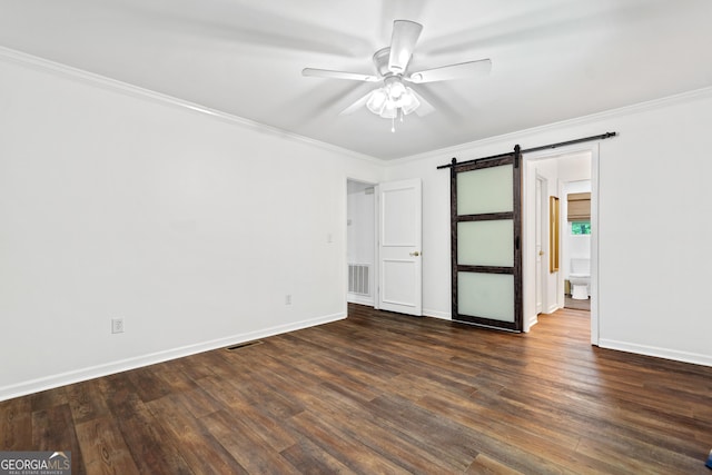 empty room with dark wood-style flooring, a ceiling fan, a barn door, and ornamental molding
