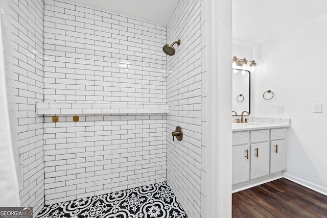 full bathroom featuring vanity, baseboards, wood finished floors, and a tile shower