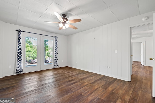 empty room with baseboards, a ceiling fan, and dark wood-style floors