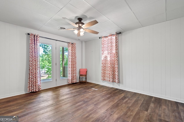 empty room with wood-type flooring, baseboards, ceiling fan, and visible vents