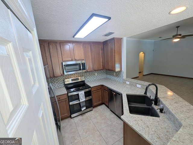 kitchen featuring visible vents, arched walkways, a sink, appliances with stainless steel finishes, and light tile patterned floors