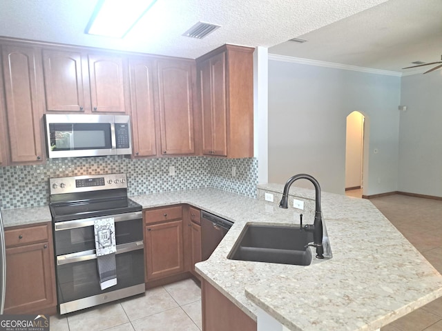 kitchen with a sink, arched walkways, stainless steel appliances, a peninsula, and visible vents