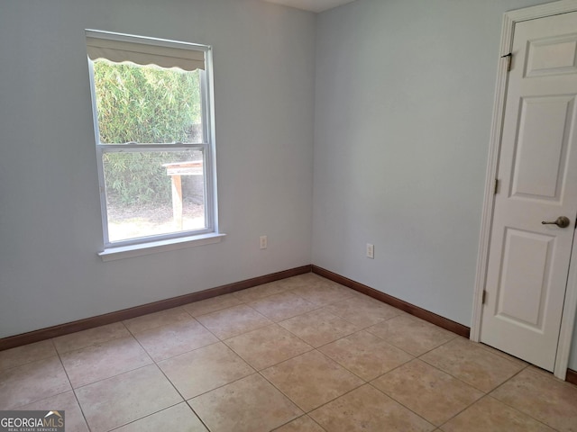 spare room with baseboards, light tile patterned floors, and a healthy amount of sunlight