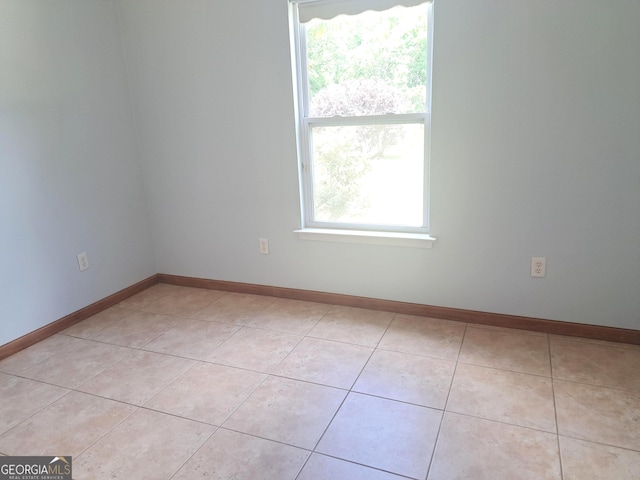 spare room featuring baseboards and light tile patterned floors