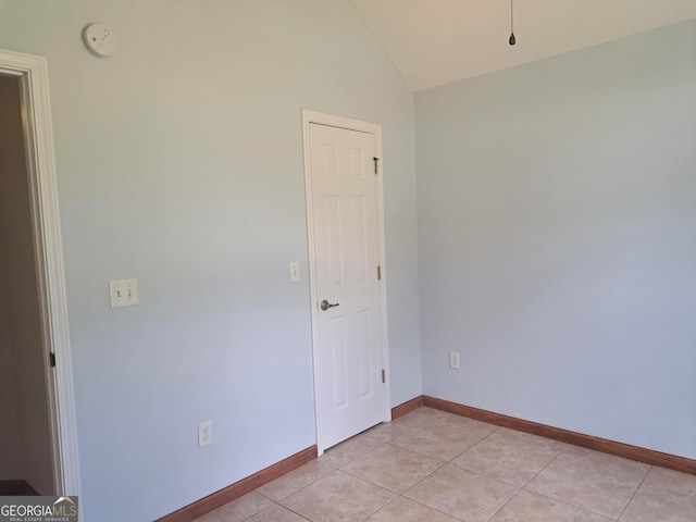 unfurnished room featuring baseboards, light tile patterned floors, and lofted ceiling