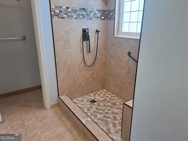 full bathroom featuring baseboards, tile patterned flooring, and a tile shower