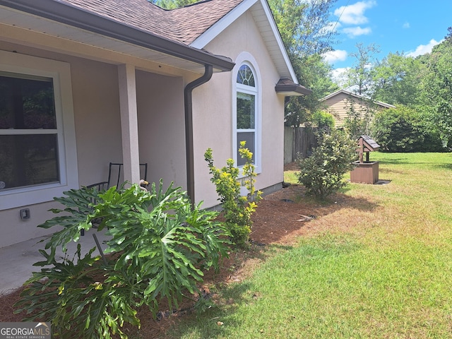 view of home's exterior with a lawn, a shingled roof, and stucco siding