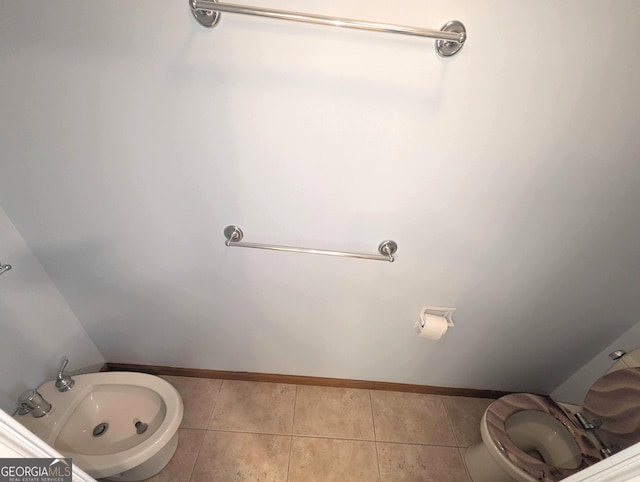 bathroom with tile patterned flooring, baseboards, and toilet