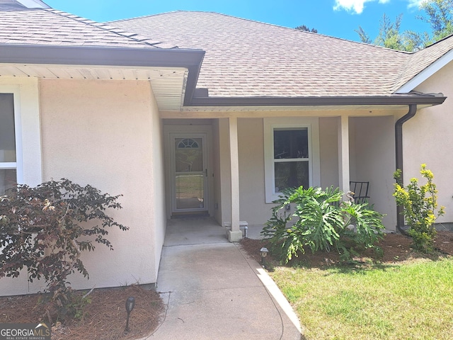doorway to property with a shingled roof and stucco siding