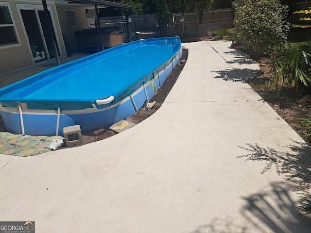 view of swimming pool with a hot tub, a patio, and fence