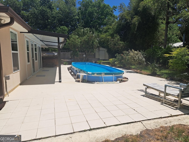 outdoor pool with fence, a patio, an outbuilding, and a shed