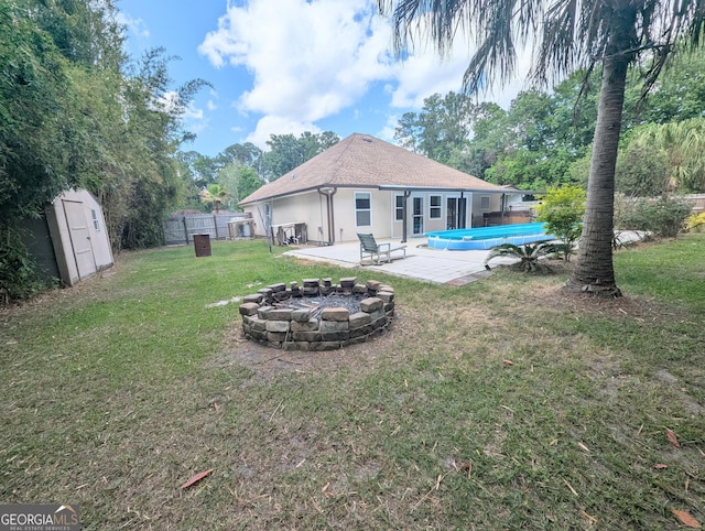 rear view of house featuring fence, a patio area, a lawn, a swimming pool, and an outdoor fire pit