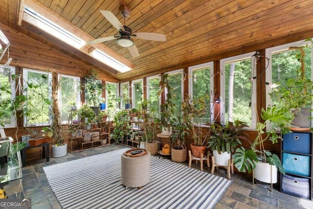 sunroom featuring stone tile floors, wooden ceiling, and vaulted ceiling with skylight
