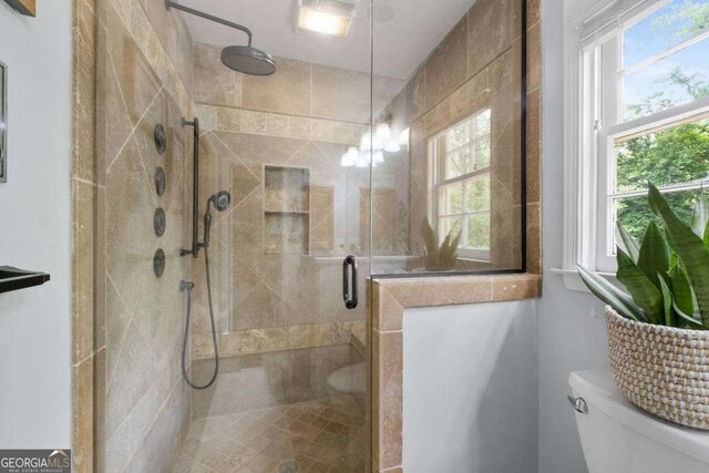 bathroom with plenty of natural light, a stall shower, and toilet