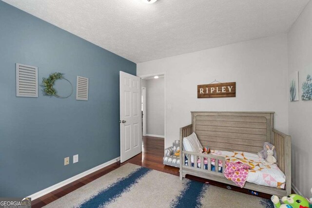 bedroom with baseboards, a textured ceiling, and wood finished floors