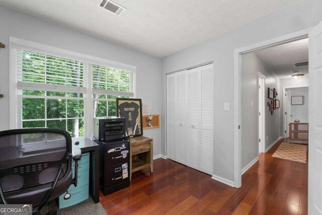 office space featuring a textured ceiling, baseboards, wood finished floors, and visible vents