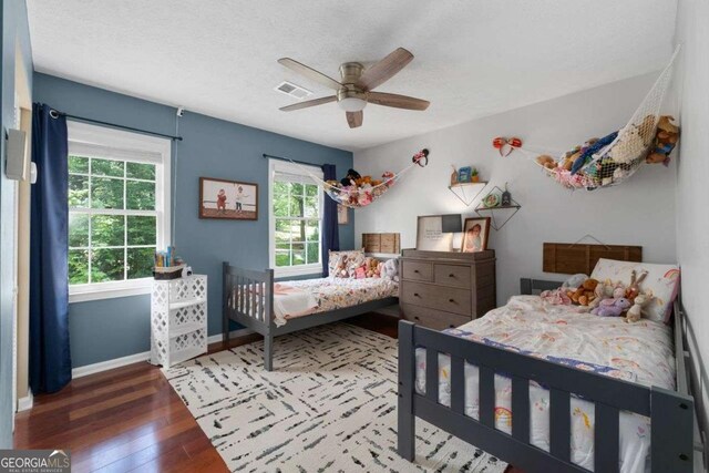 bedroom with visible vents, wood-type flooring, baseboards, a textured ceiling, and a ceiling fan