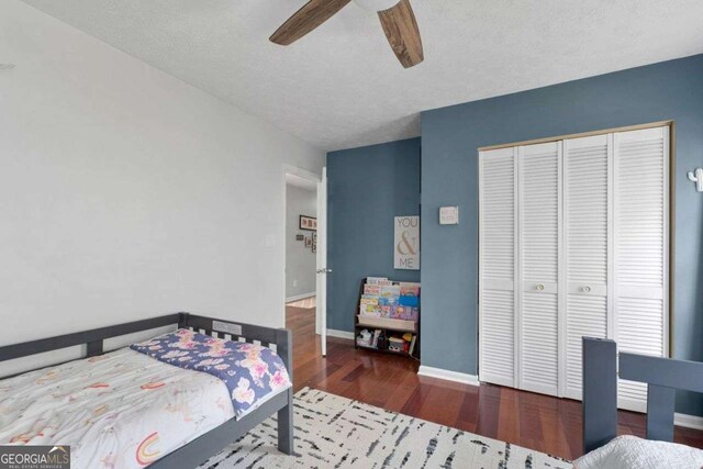 bedroom featuring baseboards, ceiling fan, wood finished floors, and a closet