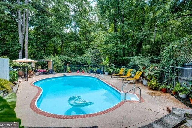 outdoor pool featuring fence and a patio