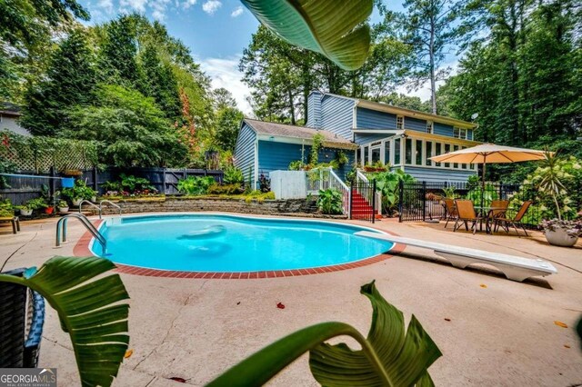 view of pool with a diving board, fence, a patio area, and a fenced in pool