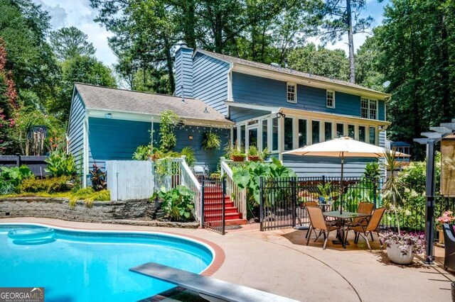 rear view of property featuring a fenced in pool, fence, a patio area, and stairway