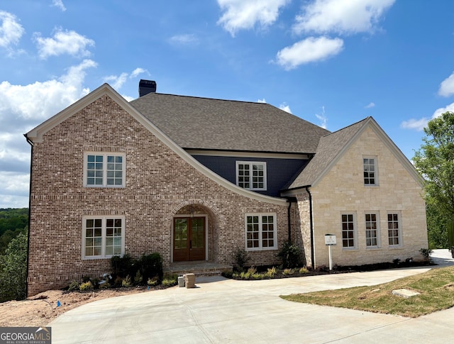 5753 Brendlynn Dr, Suwanee, GA 30024 - view of front facade with a chimney, a shingled roof, brick siding, and french doors