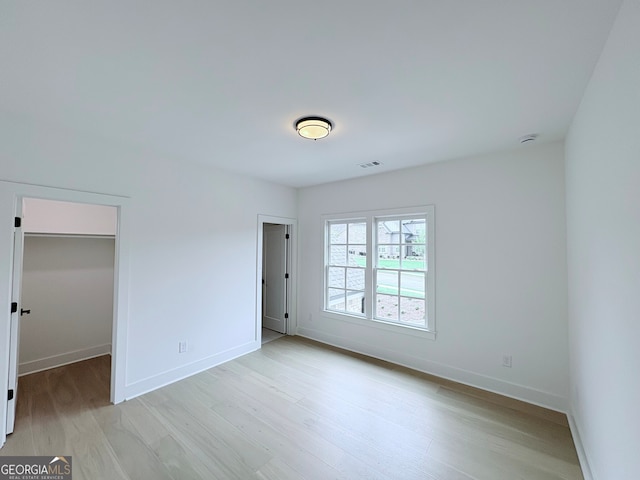 5753 Brendlynn Dr, Suwanee, GA 30024 - unfurnished bedroom with light wood-type flooring and a walk in closet
