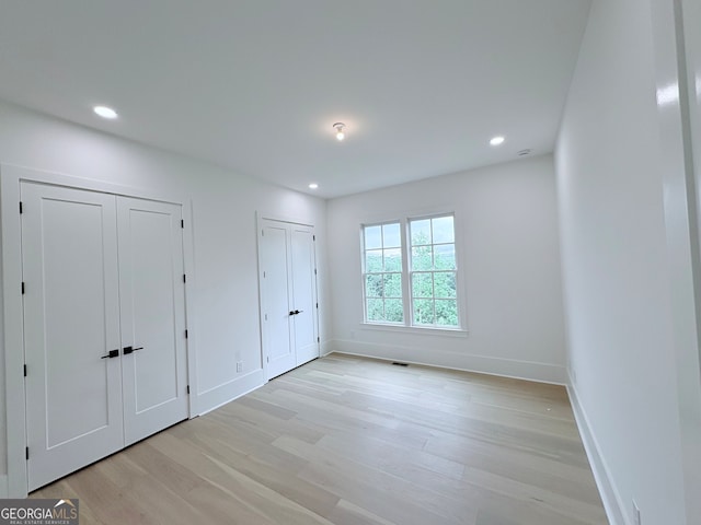 5753 Brendlynn Dr, Suwanee, GA 30024 - unfurnished bedroom featuring two closets, light wood finished floors, and recessed lighting