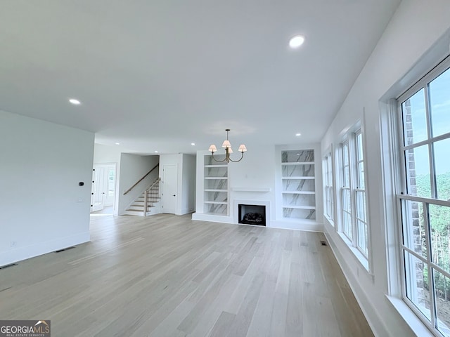 5753 Brendlynn Dr, Suwanee, GA 30024 - unfurnished living room featuring light wood-style flooring, stairs, a chandelier, recessed lighting, and built in shelves