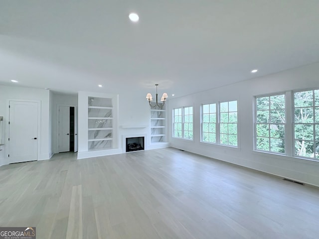 5753 Brendlynn Dr, Suwanee, GA 30024 - unfurnished living room featuring a chandelier, light wood-style floors, recessed lighting, and built in shelves