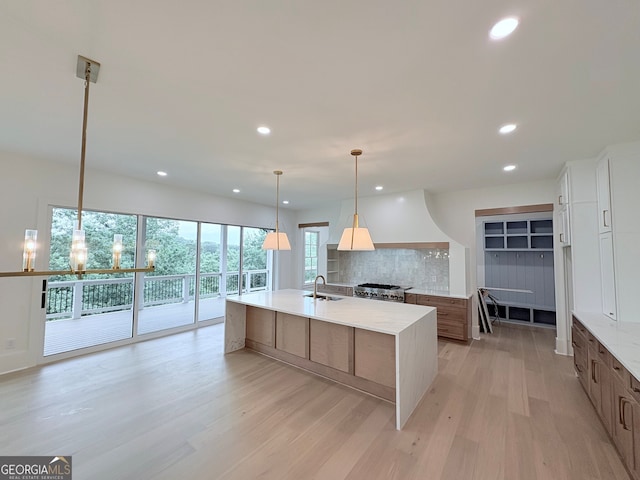 5753 Brendlynn Dr, Suwanee, GA 30024 - kitchen with light wood finished floors, recessed lighting, backsplash, an island with sink, and white cabinets