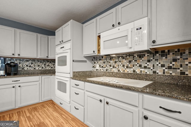 224 Pine Bluff Dr, Kingsland, GA 31548 - kitchen with white appliances, white cabinetry, light wood-style flooring, and tasteful backsplash