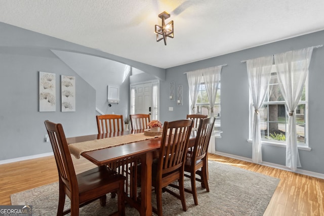 224 Pine Bluff Dr, Kingsland, GA 31548 - dining room with light wood-style floors, arched walkways, baseboards, and a textured ceiling
