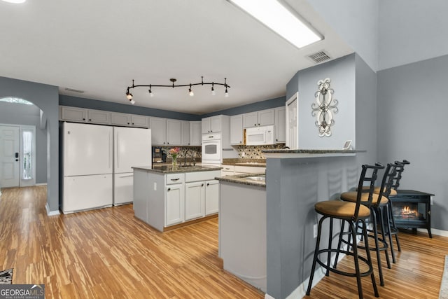 224 Pine Bluff Dr, Kingsland, GA 31548 - kitchen featuring visible vents, white appliances, light wood-style floors, a sink, and dark stone countertops