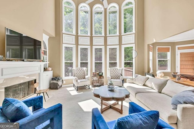 carpeted living room with a fireplace and a towering ceiling