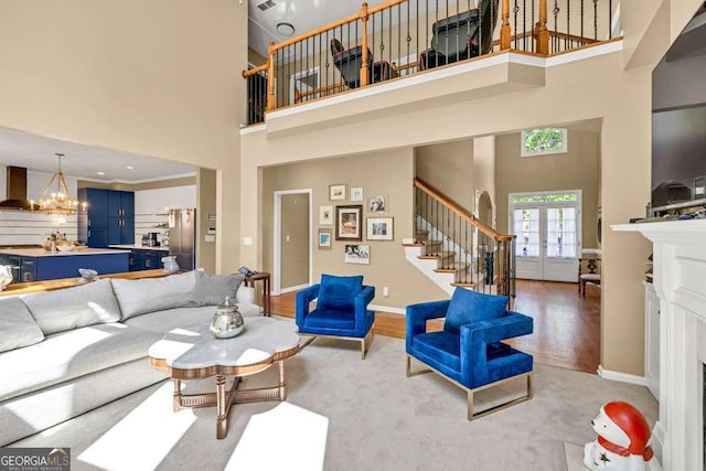living area with stairway, a high ceiling, wood finished floors, and a notable chandelier