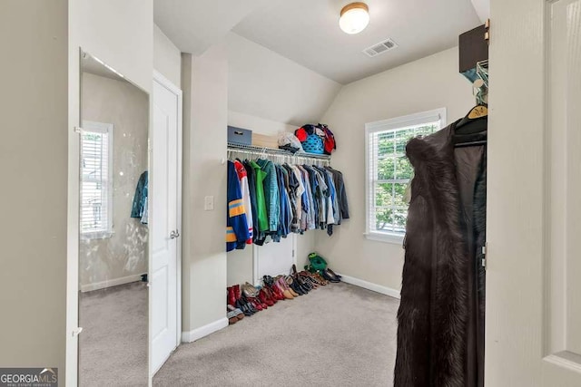 spacious closet with carpet flooring, lofted ceiling, and visible vents