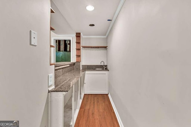 interior space with crown molding, a sink, and light wood-style floors
