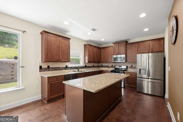 3940 Village Estates Ct, Cumming, GA 30040 - kitchen featuring appliances with stainless steel finishes, backsplash, dark wood finished floors, light stone countertops, and a center island