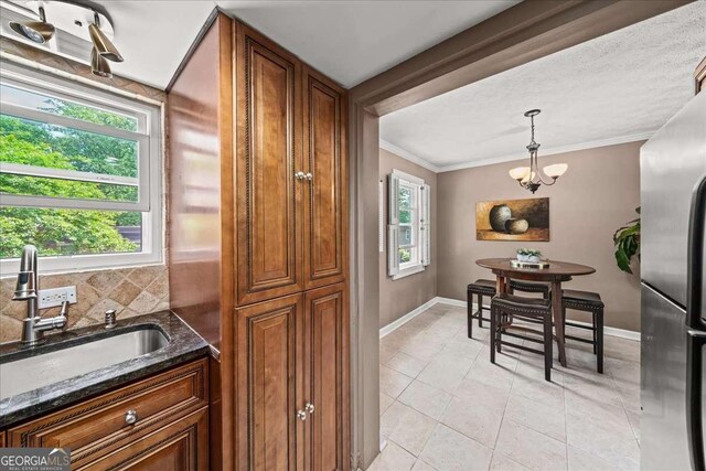 331 Lakemoore Dr NE Unit C, Atlanta, GA 30342 - kitchen featuring brown cabinetry, a sink, freestanding refrigerator, dark stone counters, and ornamental molding