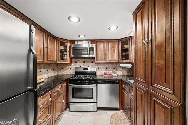 331 Lakemoore Dr NE Unit C, Atlanta, GA 30342 - kitchen featuring stainless steel appliances, decorative backsplash, light tile patterned flooring, and dark stone countertops