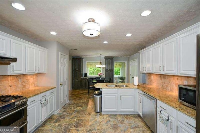 kitchen featuring a sink, stainless steel appliances, recessed lighting, white cabinetry, and a peninsula