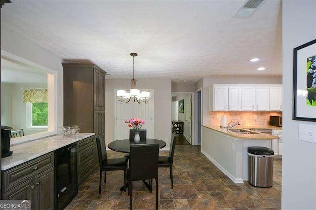 dining area featuring a notable chandelier, recessed lighting, stone finish flooring, wine cooler, and visible vents