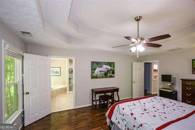 bedroom with visible vents, wood finished floors, baseboards, a tray ceiling, and a ceiling fan