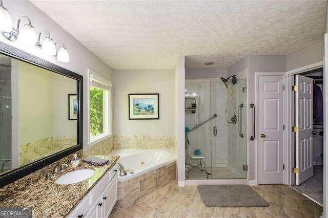 bathroom featuring a whirlpool tub, a textured ceiling, a stall shower, and vanity