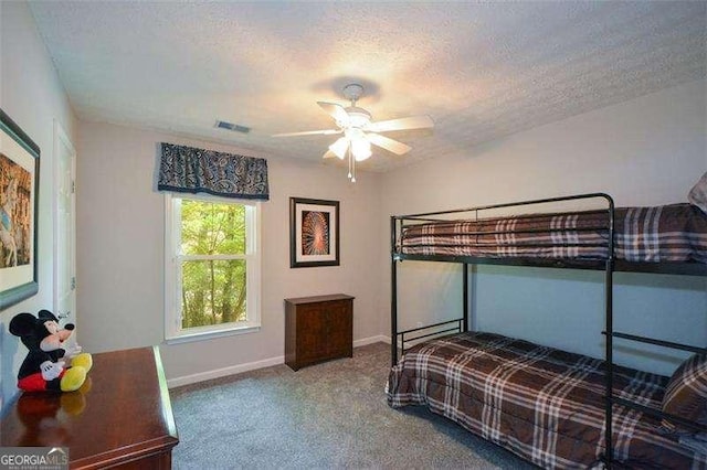 bedroom featuring ceiling fan, a textured ceiling, visible vents, carpet floors, and baseboards