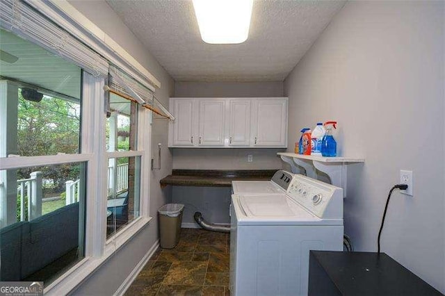 washroom with baseboards, stone finish floor, a textured ceiling, washing machine and clothes dryer, and cabinet space